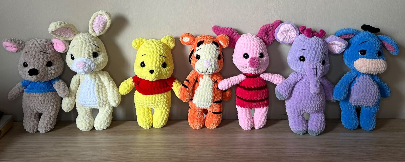 Sette peluche in ciniglia in fila: Ro, Tappo, Winnie the Pooh, Tigro, Pimpi, Effy e Ih-Oh